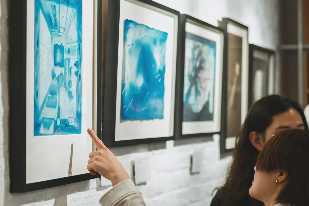 Woman pointing at original blue artwork on display at a New Orleans gallery